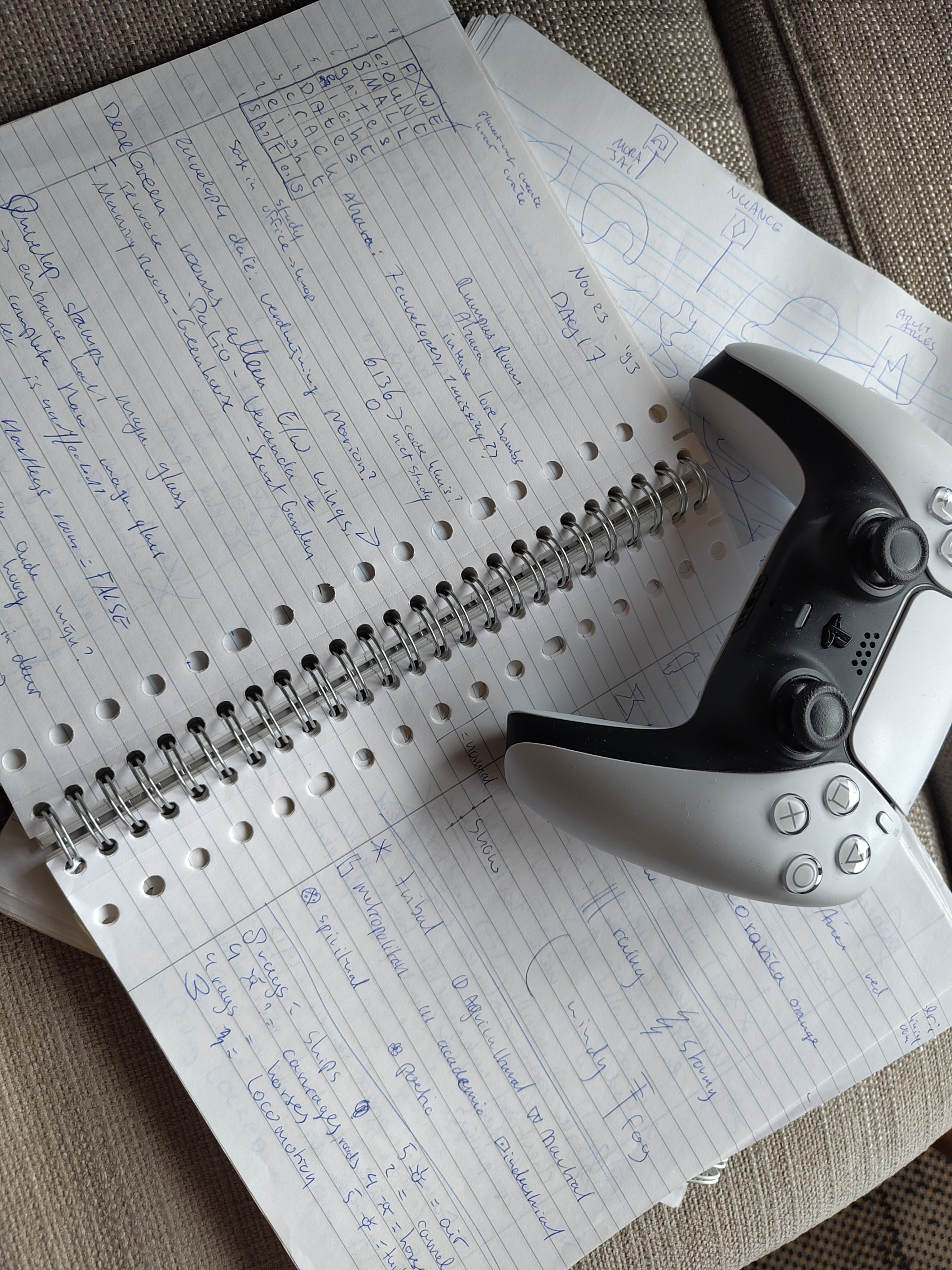 Een notitieblok gevuld met frantic Blue Prince aantekeningen, met daarop een PS5 controller